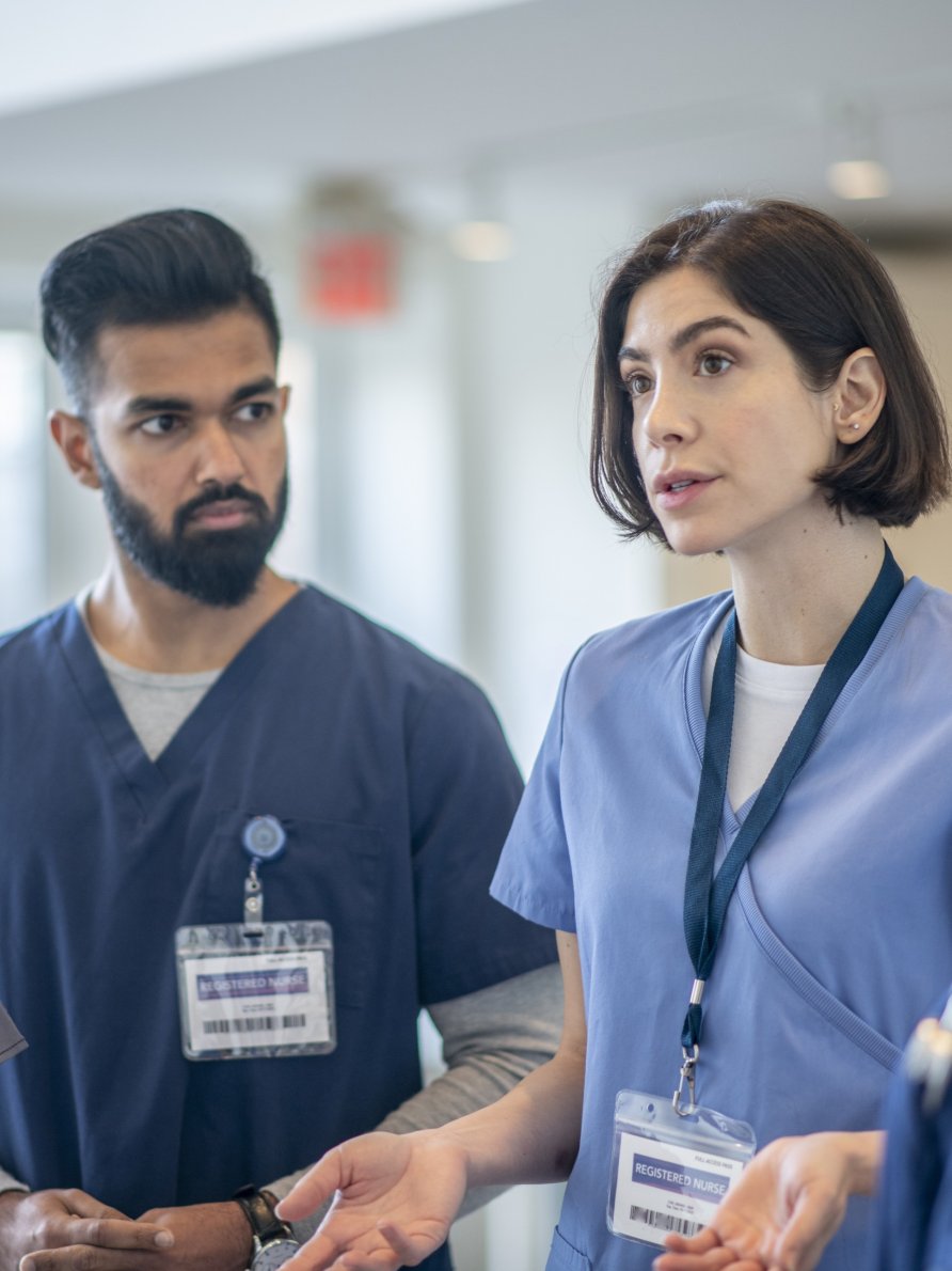 2 health care workers speaking to colleagues in a care environment.