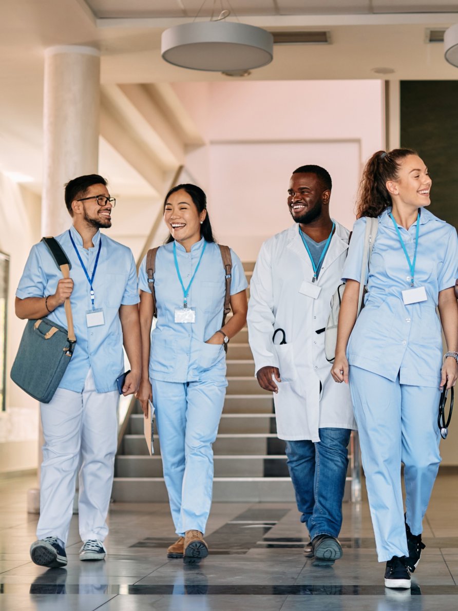 4 health care professionals walking through a hallway smiling